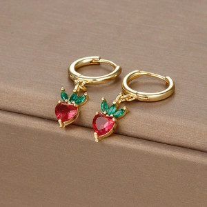 Macro view of gold-plated strawberry earrings with red heart-shaped crystals