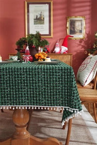 Close-up of green and black plaid tablecloth with white snowflake patterns and pom-poms