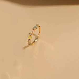 Macro detail of 14K gold plated ring featuring colorful enamel flowers and tiny gemstones