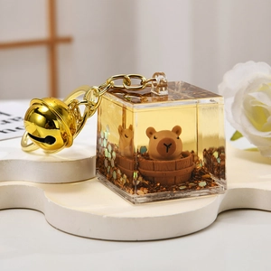 Detail of creative Capybara liquid quicksand keychain with gold glitter and metal bell