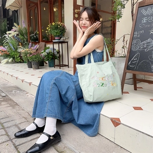Photo de style de vie d'un sac cabas en toile vert clair avec broderie Lucky en plein air