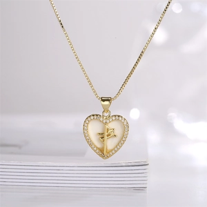 Close-up of gold heart pendant necklace with zircon inlay on white books