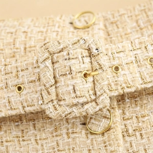 Textured sleeveless beige vest for women featuring a gold buckle belt and tweed fabric