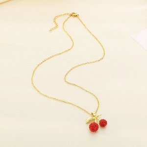 Macro detail of gold cherry pendant necklace with sparkling red rhinestones