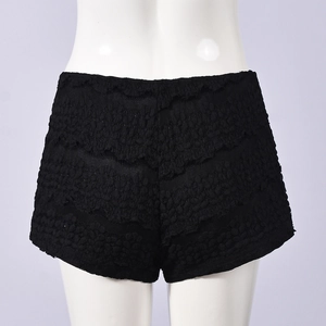 Detaillierte Makroansicht der schwarzen Spitzentextur und Blumenmuster auf Damen-Hotpants