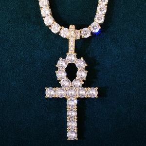 Macro shot of gold Ankh pendant with sparkling cubic zirconia on blue velvet