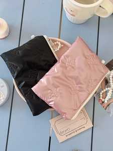 Close-up of quilted bow pattern on soft satin coin purses in black and pink