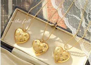 Detailed view of heart-shaped gold necklaces with zircon stars in a blue jewelry box