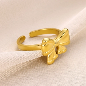 Detailed macro shot of a golden bow-shaped adjustable ring on elegant beige satin fabric