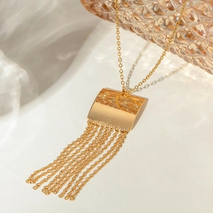 Detailed view of polished gold rectangular plate and elegant long fringe chain tassels