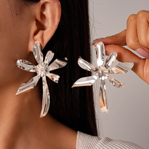 Detailed close-up of large silver double-layered metal flower earrings on model