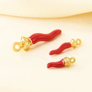 Detailed view of three red enamel chili pendants in various sizes with gold-plated loops