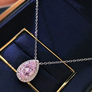Macro shot of pink pear-cut zircon necklace with halo setting in a blue velvet box