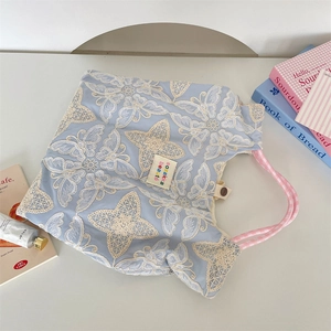 Gros plan sur la broderie papillon et la poignée à carreaux roses du sac bleu clair