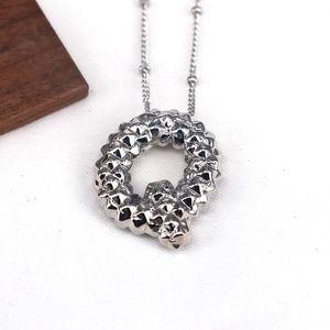 Macro detail of silver letter Q pendant featuring a unique textured rock surface finish