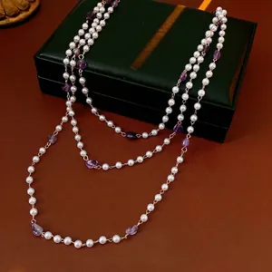 Vintage style necklace featuring white pearls and purple amethyst stones on leather box