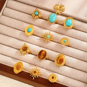 Macro view of twelve gold rings with turquoise and tiger eye stones in a velvet box
