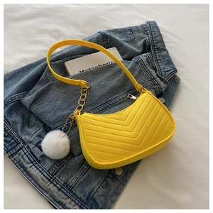 Détail du sac sous l'aisselle en feutre jaune avec matelassage en V et pompon en fourrure