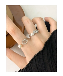 Detailed view of silver rings featuring clover leaf with pearl and wavy diamond band