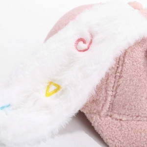 Detailansicht der rosa Plüsch-Wintermütze mit bunten Stickereien auf weißem Kunstpelzbesatz