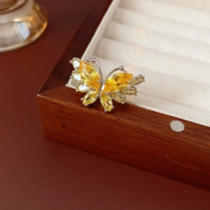 Détail d'une bague papillon avec zircons jaunes sur un support en velours blanc doux