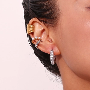 Close-up of gold wavy ear cuff, pearl clip, and silver pavé hoop earrings on ear