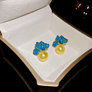 Détail de boucles d'oreilles fleurs bleues avec bordure dorée et perles en coffret