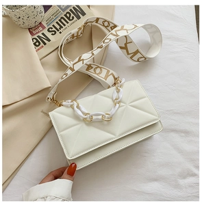 Detail of cream crossbody bag featuring geometric quilting and wide fabric shoulder strap