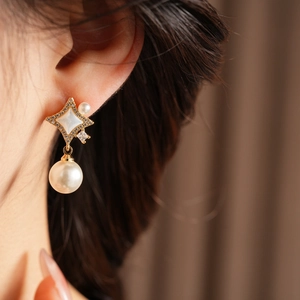 Détail de boucles d'oreilles perles en forme d'étoile avec base dorée et strass brillants