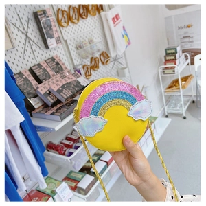 Detail of yellow round kids crossbody bag featuring glitter rainbow and cloud decorations