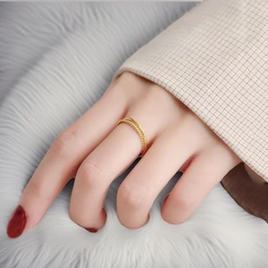 Detail of 18k gold plated stainless steel twisted rope ring on finger with soft background