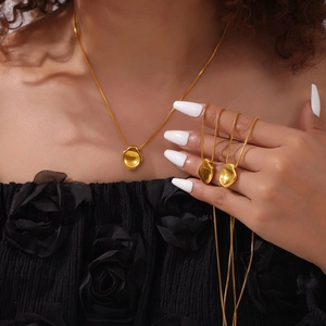 Gold box chain necklace featuring an irregular concave round pendant on female model