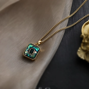 Close-up of geometric 18K gold plated square pendant with dark green shell inlay