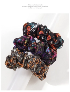 Detailed view of three Halloween scrunchies with pumpkin, star, and skull prints