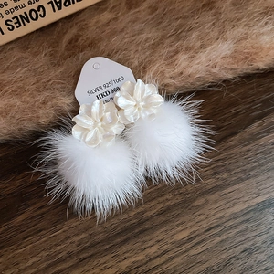 Gros plan de boucles d'oreilles en argent 925 avec fleur blanche et pompon doux