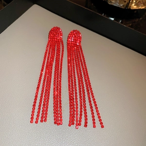 Macro detail of red rhinestone long tassel drop earrings on gray jewelry tray