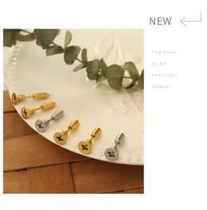 Detailed view of gold and silver screw-shaped stud earrings on a ceramic dish