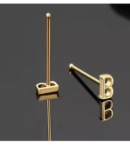 Macro-opname van 925 sterling zilveren gouden letter B oorknopjes met metaalglans
