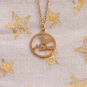 Macro view of gold Mama pendant with butterfly design on a festive star fabric