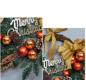 Close-up of Christmas wreath with golden balls, pine cones and Merry Christmas lettering