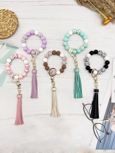 Close-up of leopard print beads and tassel keychains in multiple colors on white wood