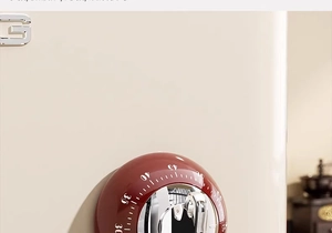Close-up of magnetic red mechanical kitchen timer with chrome dial on beige surface