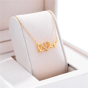 Detailed macro of gold LOVE heart pendant with sparkling crystals on velvet box