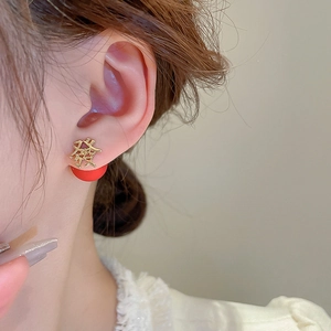 Macro shot of gold Chinese character earrings with red charm on a female model