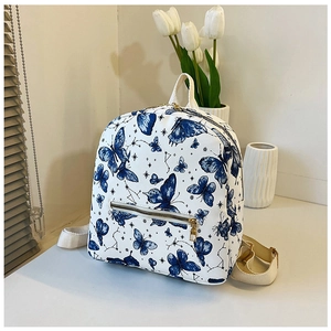 Close-up of white butterfly print backpack with golden zippers and blue star patterns