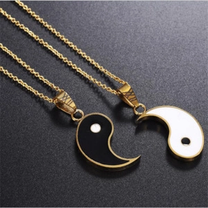 Detail shot of gold couple necklaces with interlocking black and white yin yang pendants
