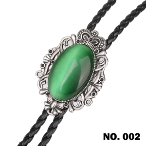 Close-up of vintage bolo tie featuring a green oval cat's eye stone and carved metal