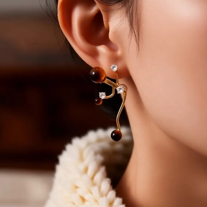 Detail of silver needle tiger eye stone earrings on model featuring golden flowing lines