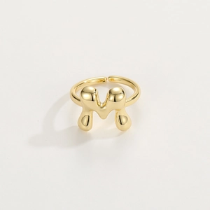 Detailed view of the gold-plated M letter ring with a smooth liquid metal finish