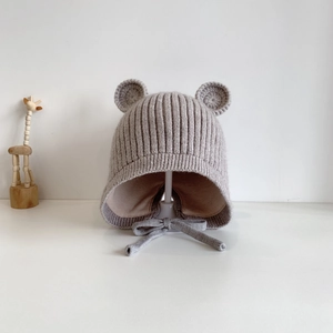 Detail einer hellgrauen Baby-Strickmütze mit süßen Bärenohren und schützenden Ohrenklappen